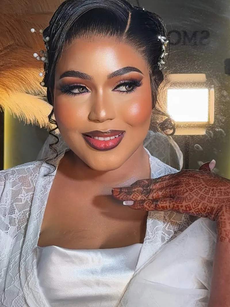 Bride smiling with a hand to her collarbone, full lashes and glowing cheeks