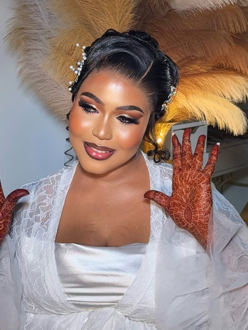 Bride with bronze eye makeup and a glossy berry lip, showing her henna-painted hands
